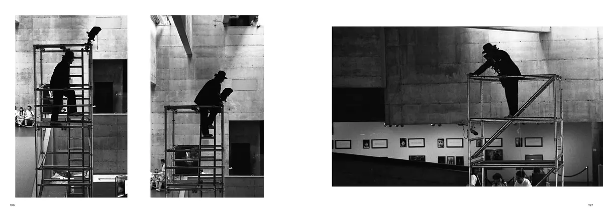 James Lee Byars in his black hat on a scaffold high in a concrete gallery, in three photographs