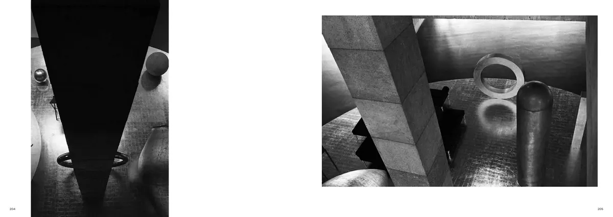 A black triangle cutting down through the frame, facing rings and columns on a polished floor