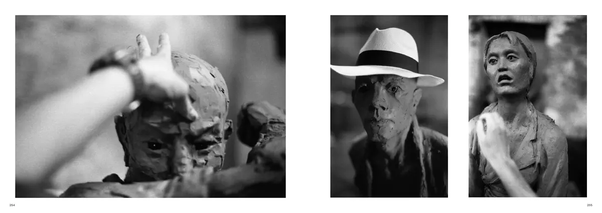 A sculptor's hand on a clay face, facing two of the figures: a man in a panama hat and a woman
