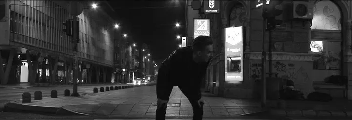 A man bent double, catching his breath on a street corner at night