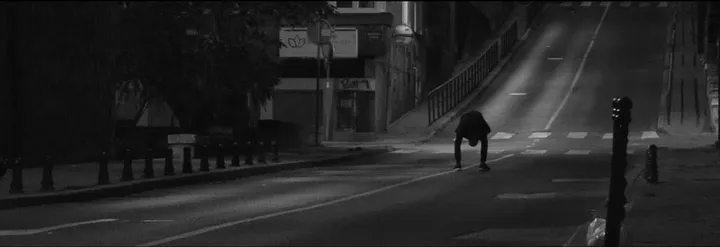 A lone figure crouched in an empty road at night